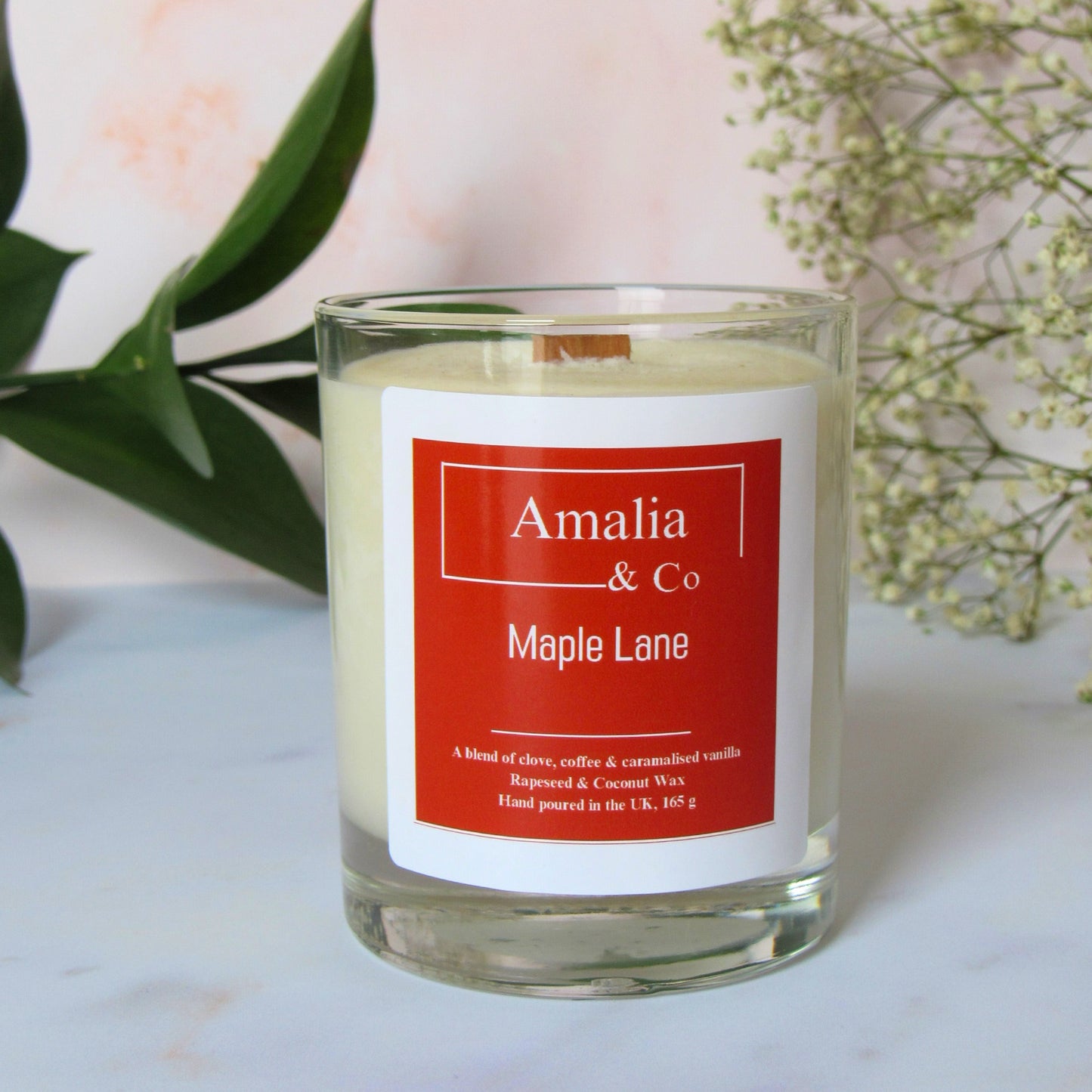 A handmade caramel and cocoa scented candle with a wooden wick, labeled 'Amalia & Co Maple Lane', in a clear glass jar.