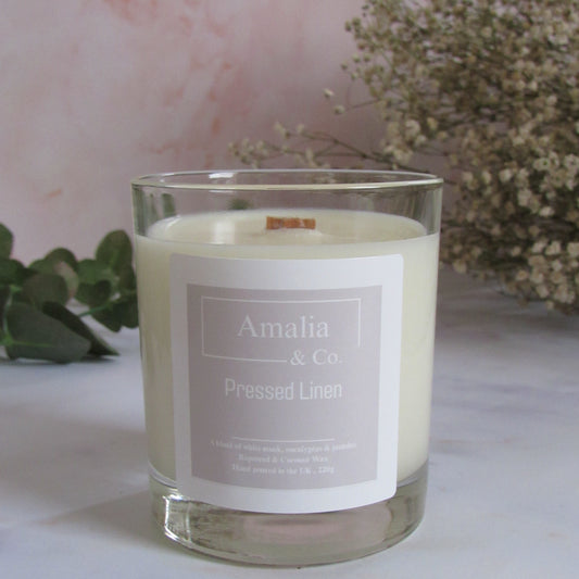 Candle in a glass jar with 'Amalia & Co.' label on a light background