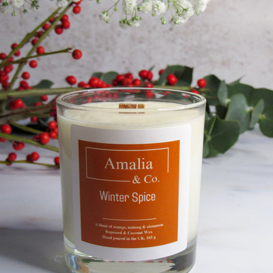 Candle with 'Amalia & Co.' label and 'Winter Spice' description, surrounded by decorative elements.